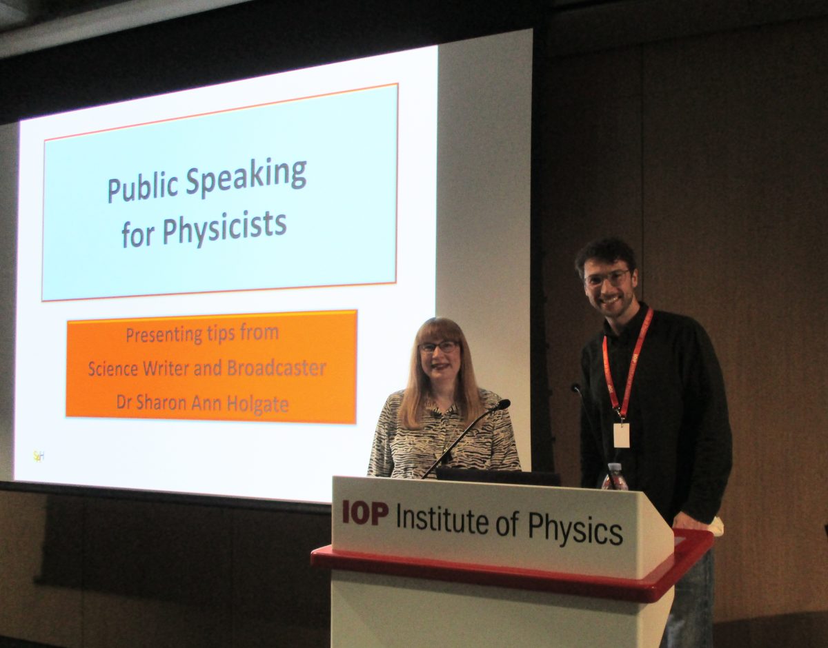 Photo of Sharon Ann Holgate and Julian Guassardo standing on stage in front of screen showing first slide from Public Speaking for Physicists workshop about to be given by Sharon Ann