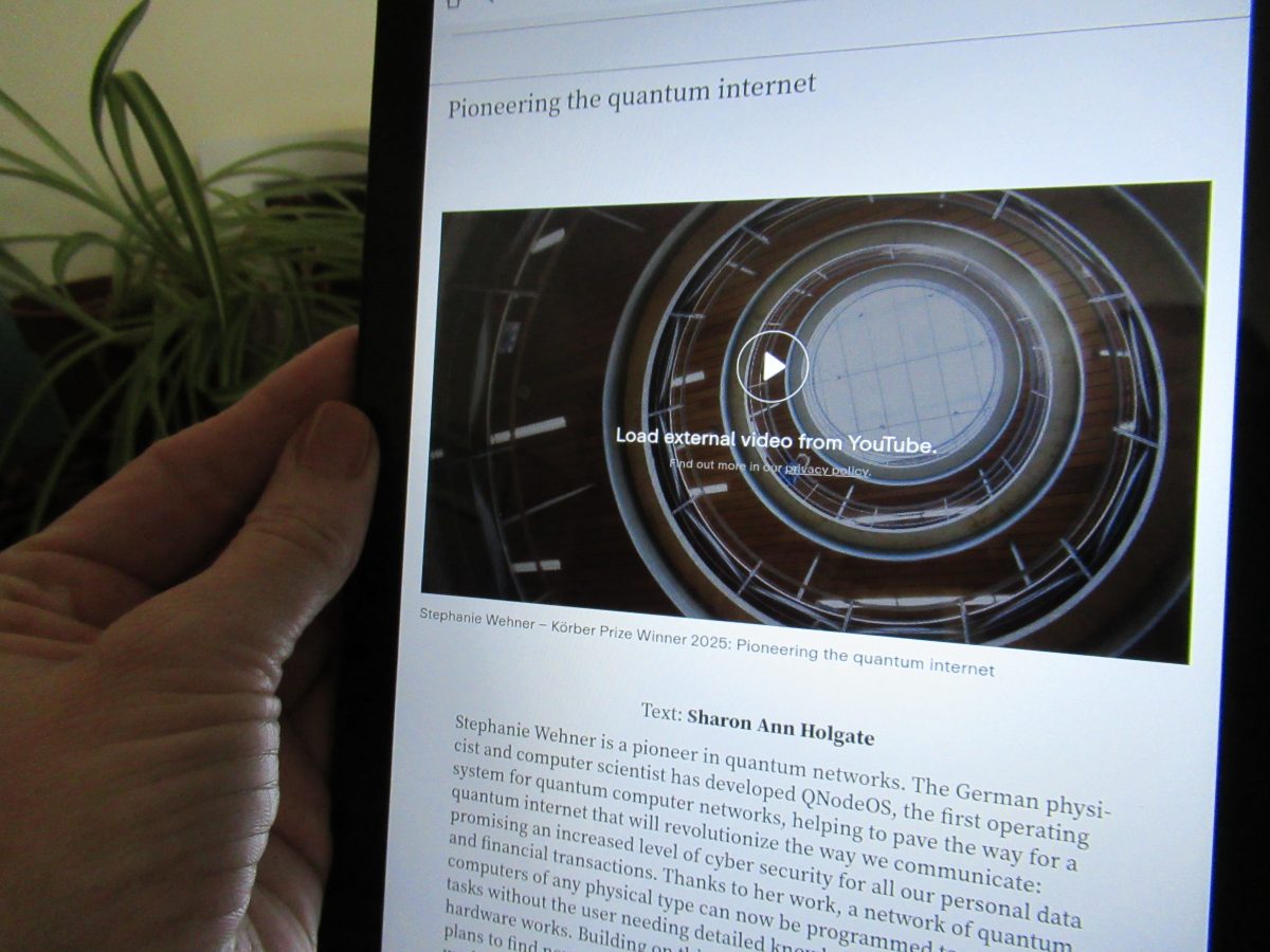 Sharon Ann's hand holding a tablet displaying part of the brochure.