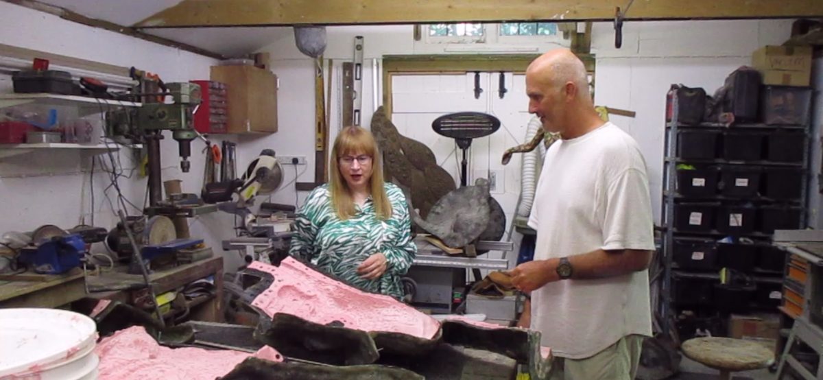Sharon Ann and Jonathan standing in his studio looking at the mould used to create a bronze resin version of one of his sculptures. This is a still from the video.